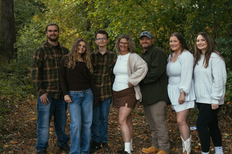 Family of seven standing together among autumn trees