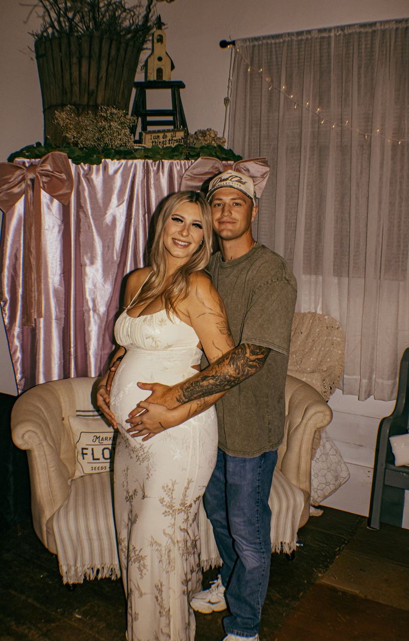Expecting couple smiling together at a pink and cream baby shower