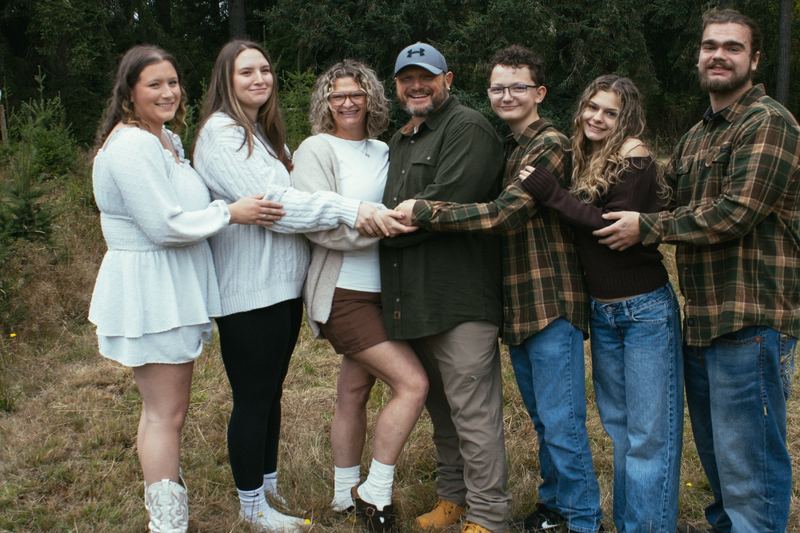 Family laughing as they stack their hands together outdoors