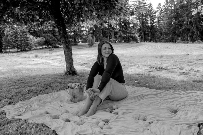 Black and white portrait of a woman sitting on a blanket under a tree